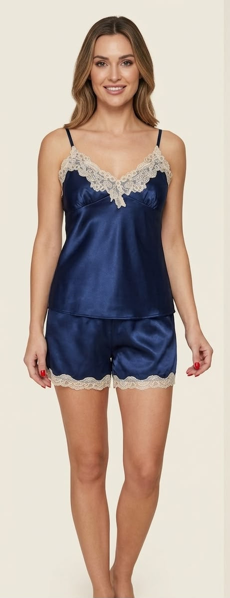 Woman wearing a navy satin pajama set with lace trim on a beige background